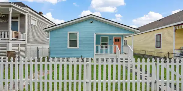 Image 2: Charming blue bungalow with a welcoming front porc