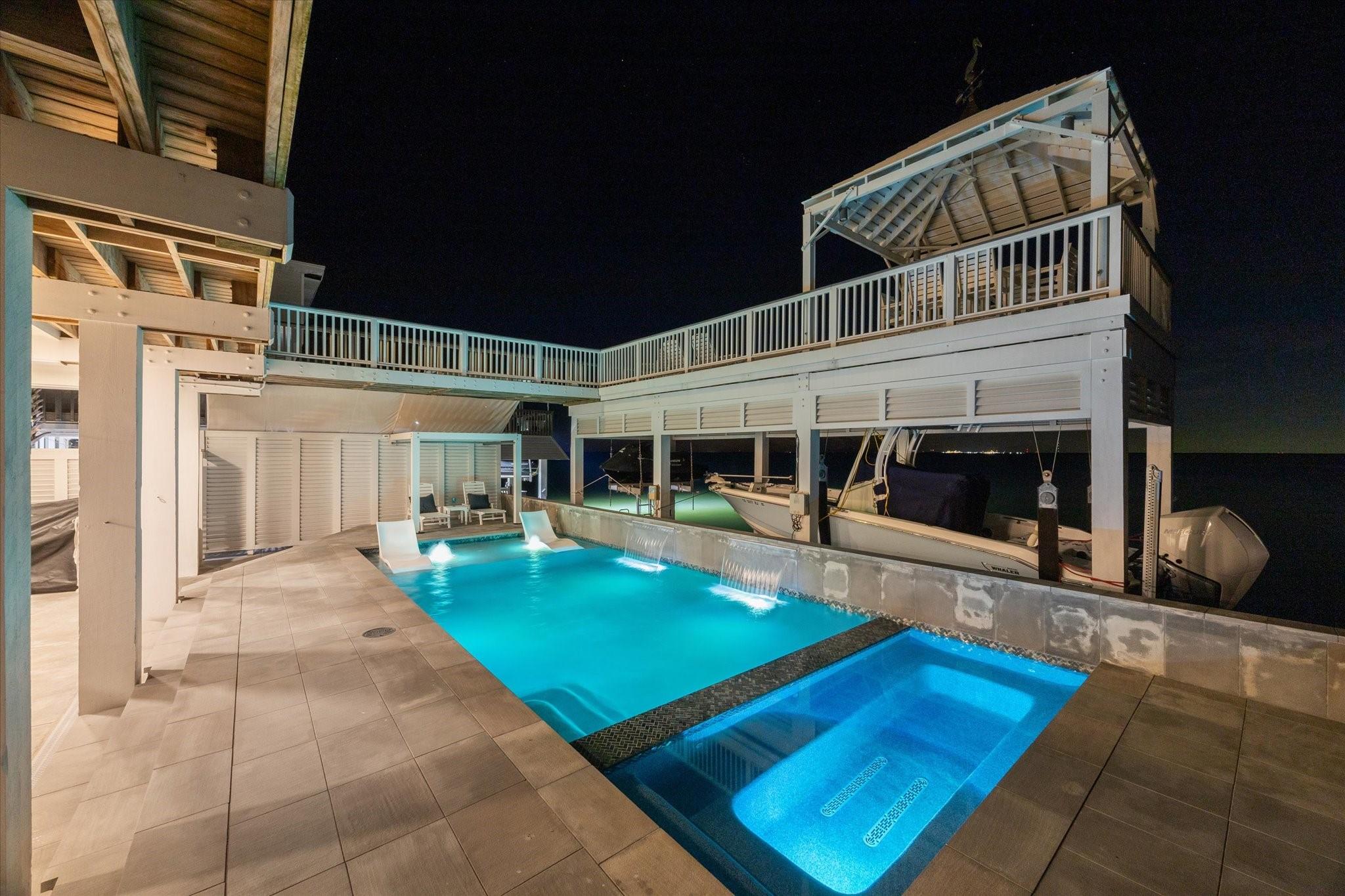 Image 3: Evening view of the pool and spa with ambient ligh