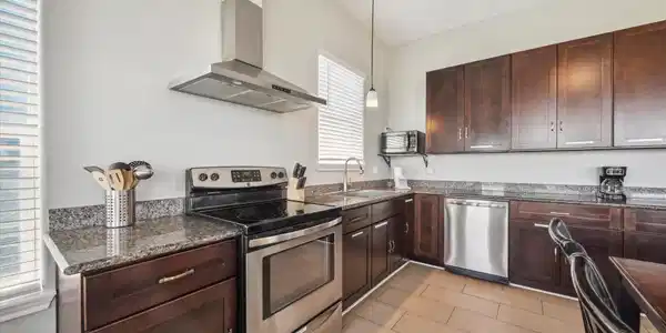 Image 3: Sleek kitchen with stainless steel appliances, gra