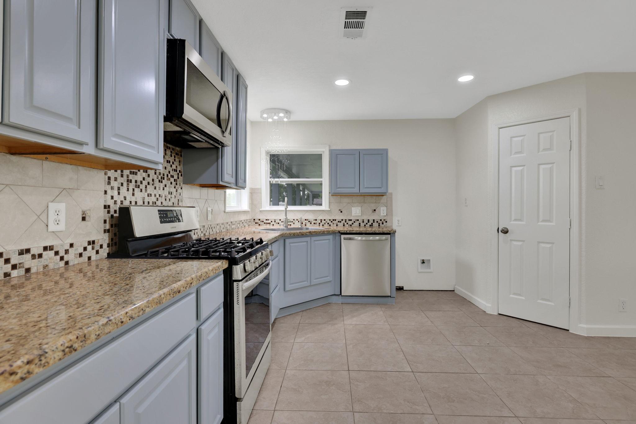 Image 3: Modern kitchen with granite countertops, mosaic ti
