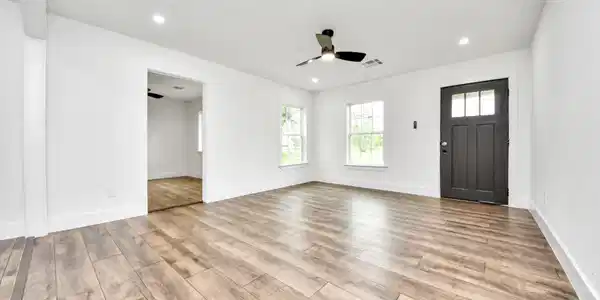 Image 4: Bright, spacious room with wood-style flooring, wh
