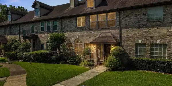 Image 2: Welcoming exterior with mature landscaping and a c