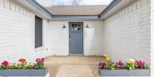 Image 2: The entrance is flanked by beautiful flowers and a