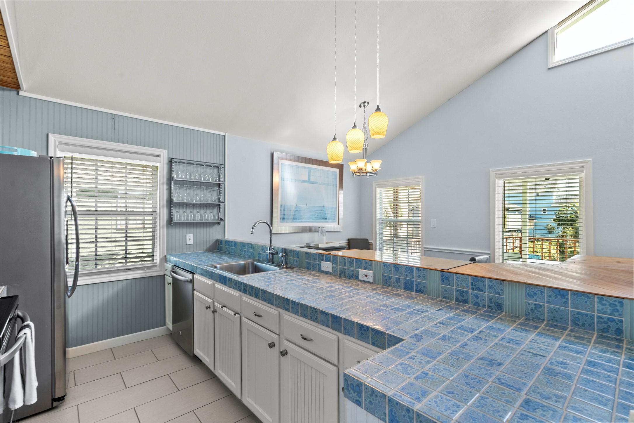 Image 3: The kitchen includes tile countertops, a double si