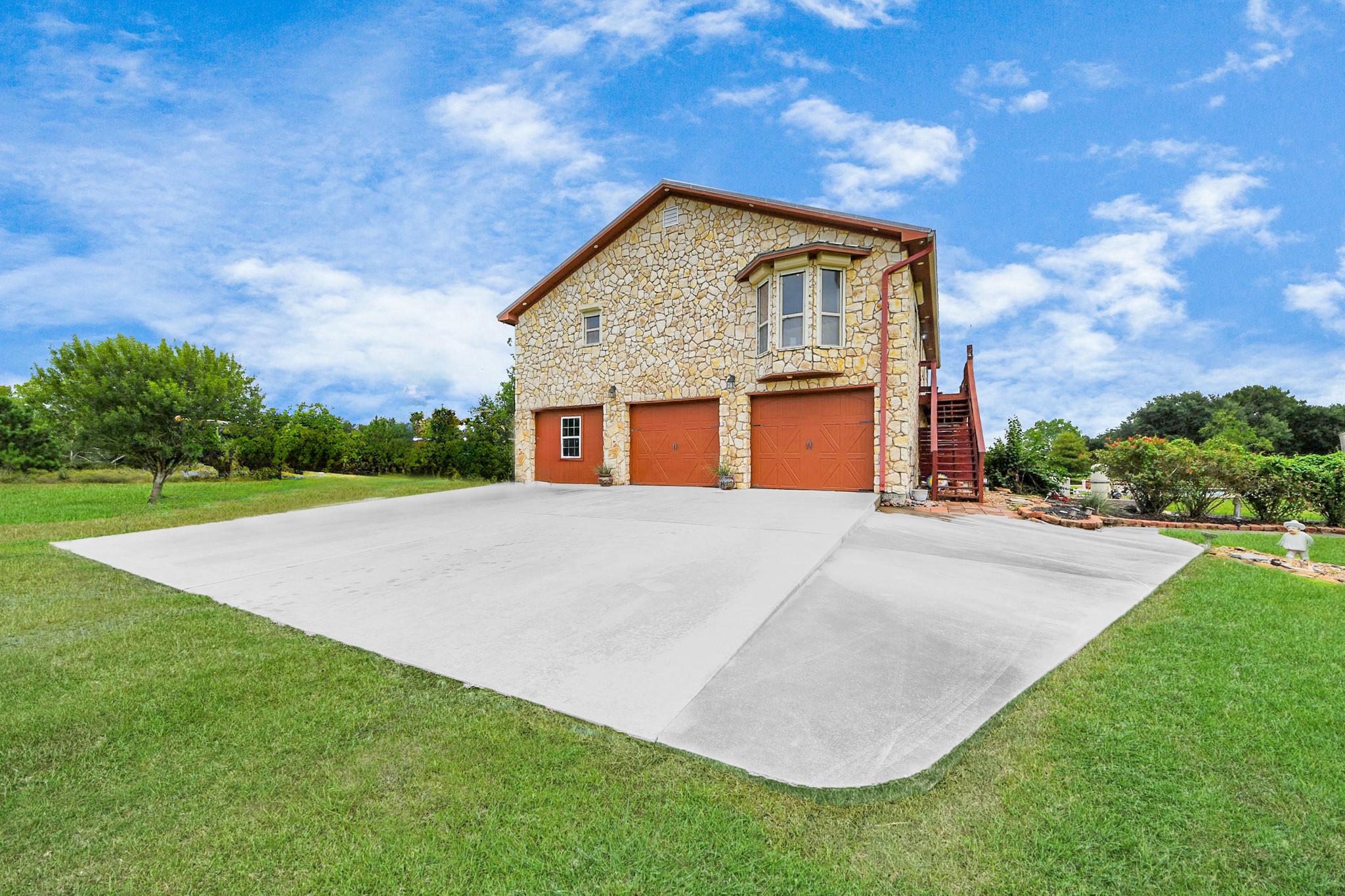 Image 3: A stone-clad exterior, expansive driveway, and two