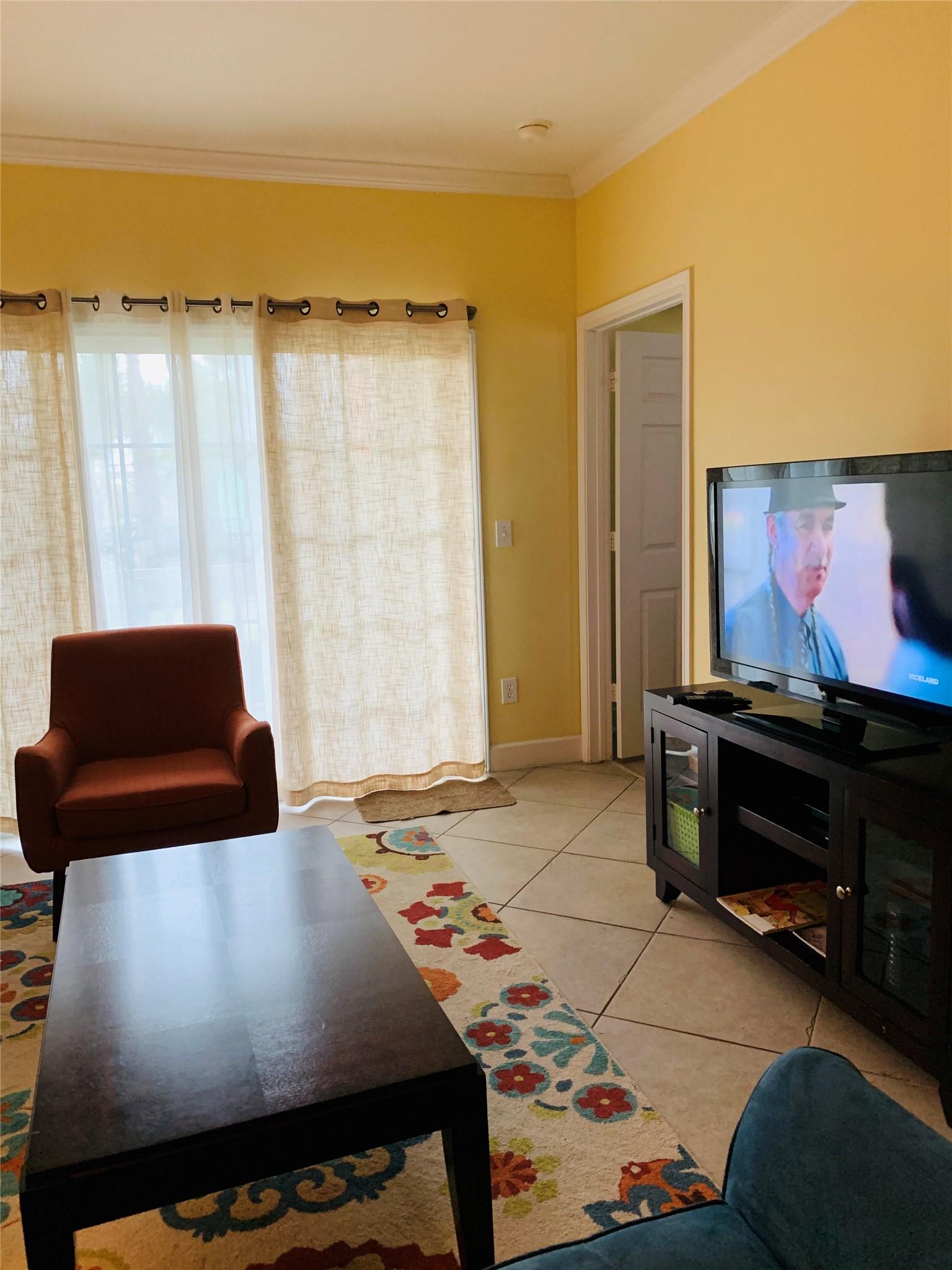 Image 3: Cozy living room with warm yellow walls, tiled flo
