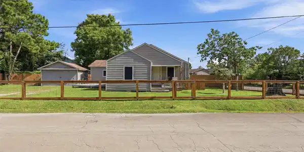 Image 3: Front view of home with fence and automatic gate