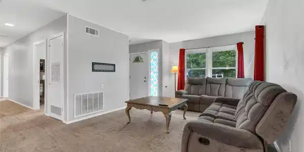 Image 3: Spacious living room with plush carpeting and larg