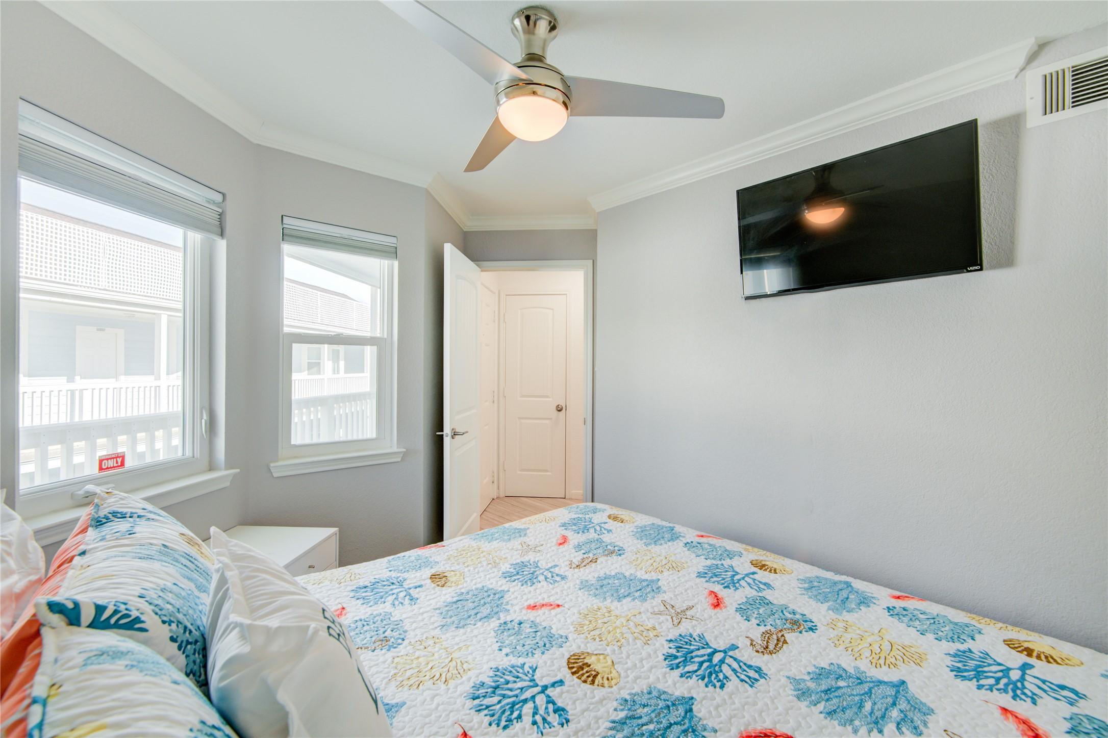 Image 3: Bright bedroom with large windows, a ceiling fan,