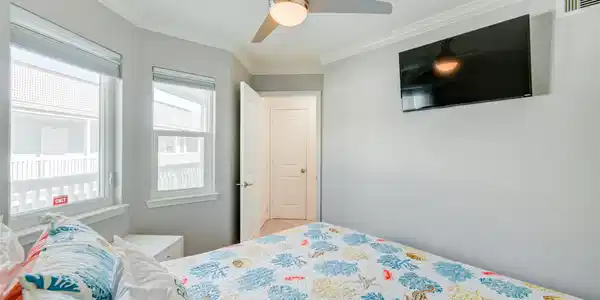 Image 3: Bright bedroom with large windows, a ceiling fan,