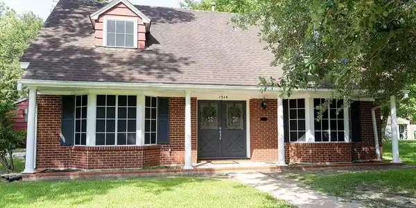 Image 2: Charming two-story brick home with a gabled roof a
