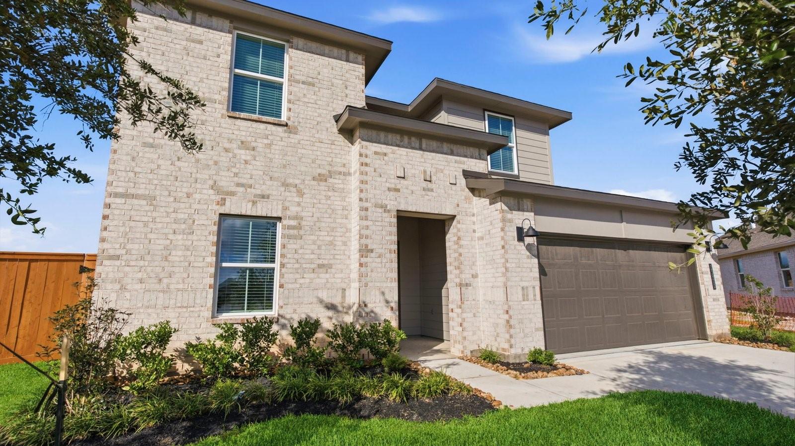 Image 2: A two-story home with brick and stone exterior wi