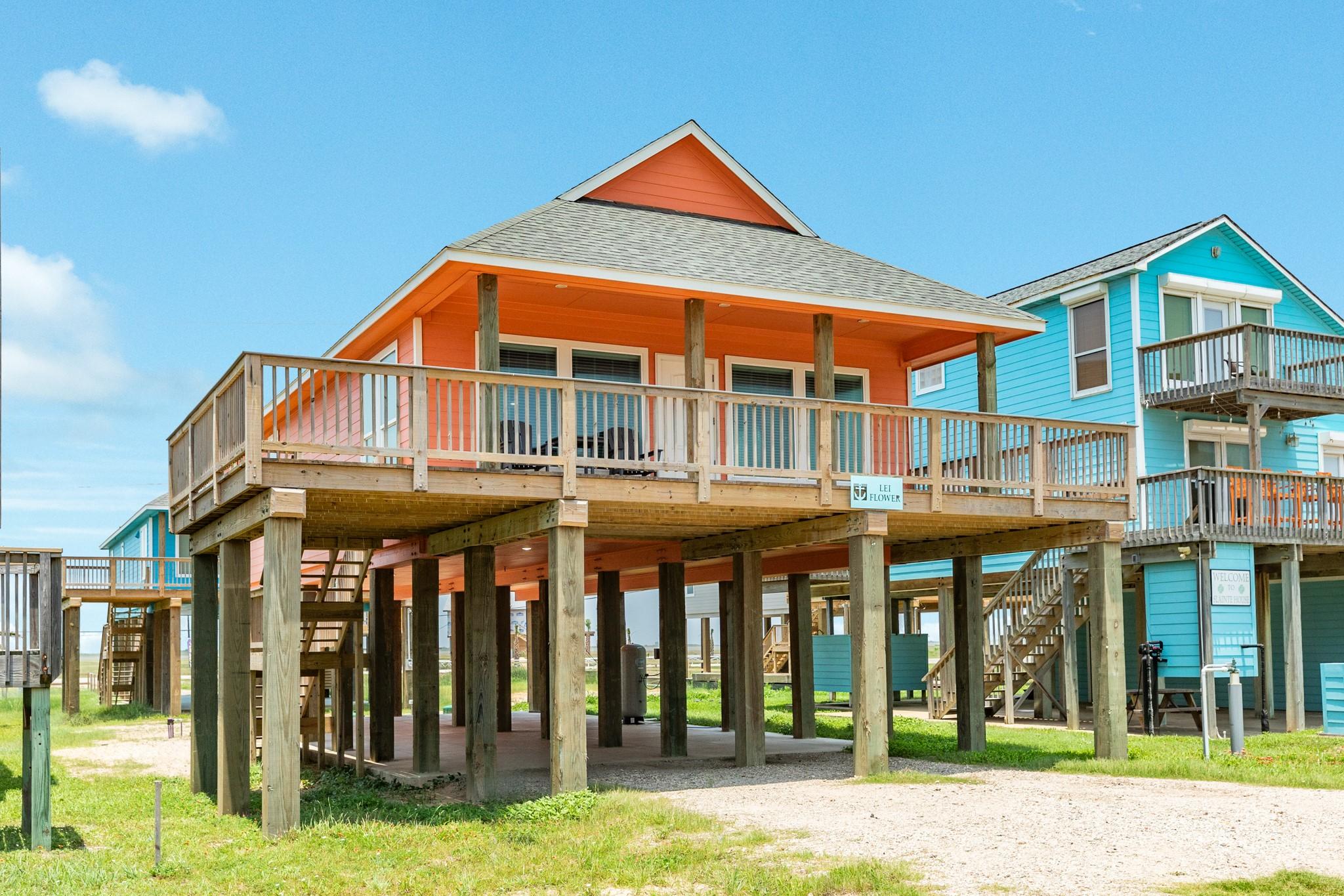 Image 2: This elevated beach house features a vibrant orang