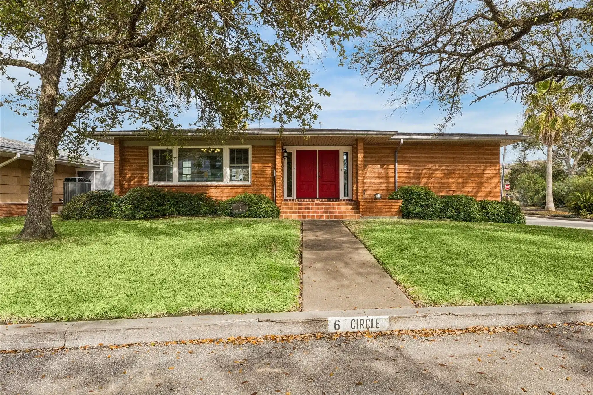 Image 1: Charming brick home with a welcoming red front doo