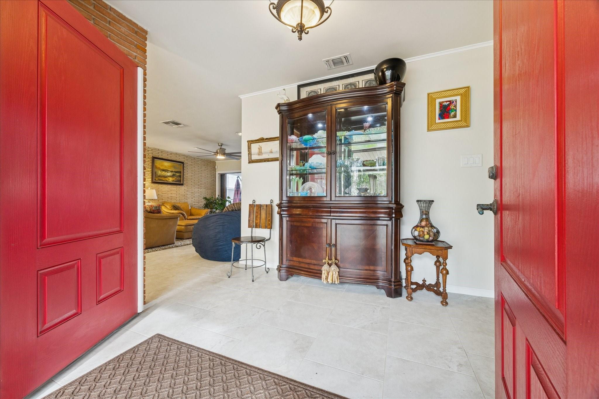 Image 2: Inviting entryway with vibrant red doors opens to