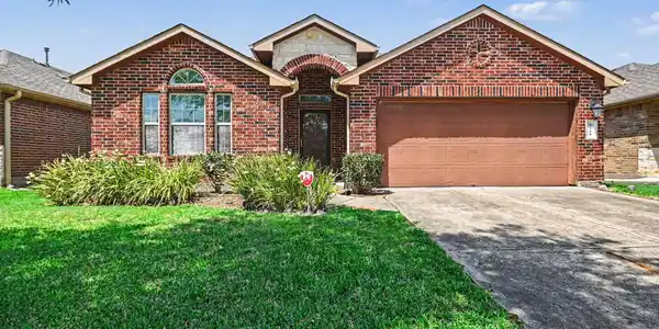 Image 2: This brick home boasts a warm and inviting covered
