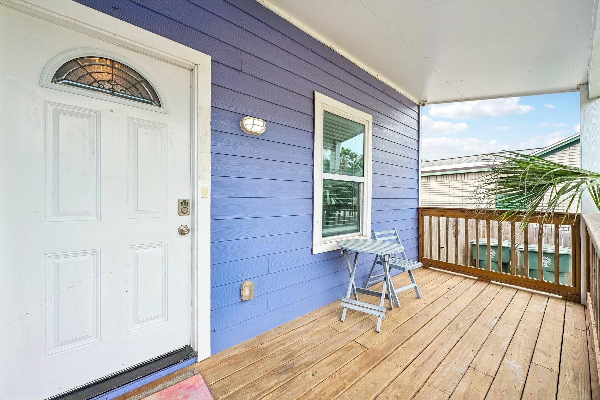 Image 4: Covered front porch with warm wood decking and rai