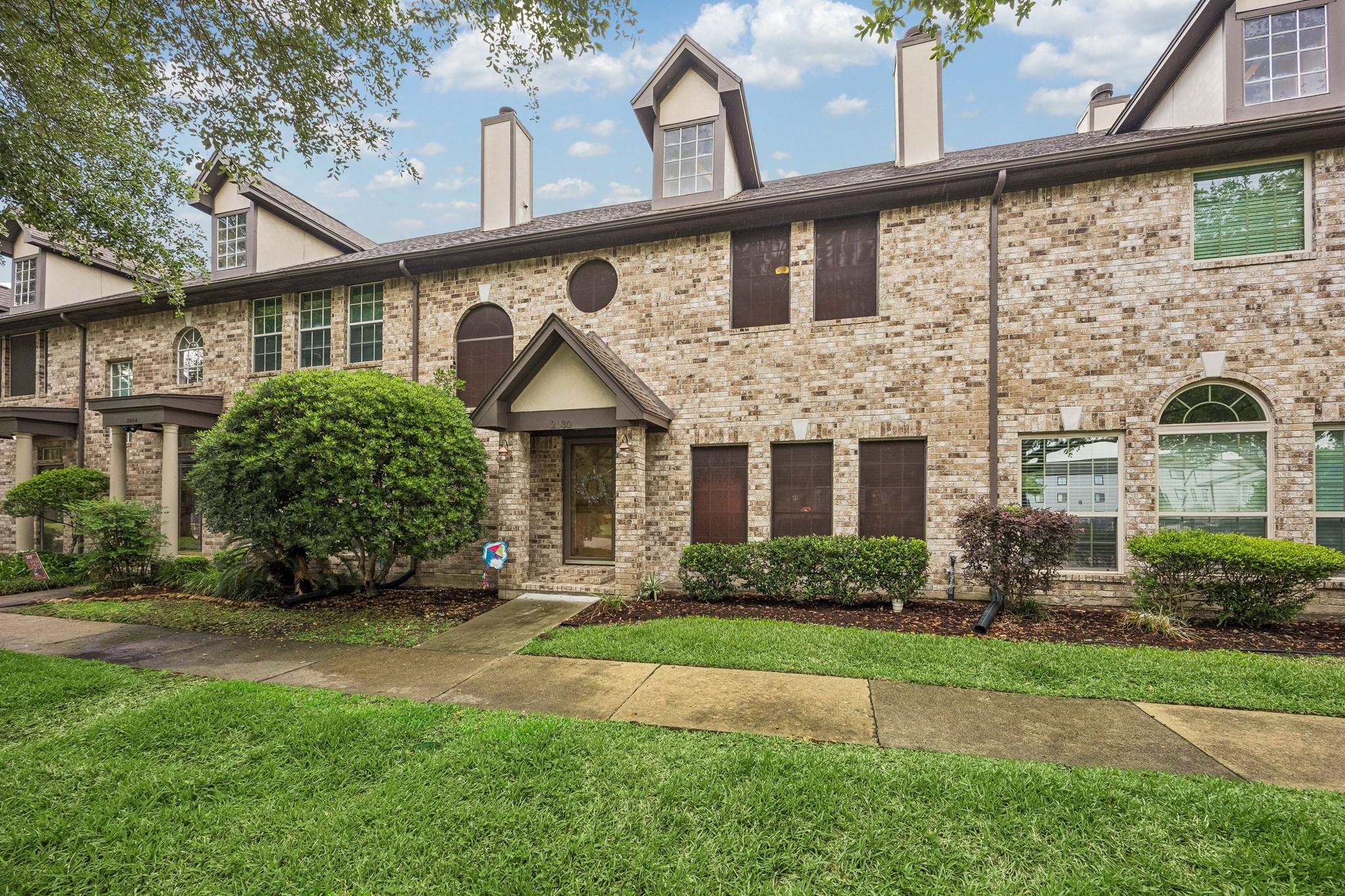 Image 1: Charming townhouse with a brick exterior, featurin