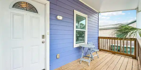 Image 4: Covered front porch with warm wood decking and rai