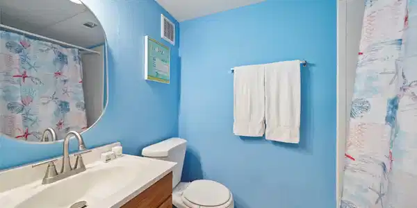 Image 3: This bathroom features bright blue walls, a white