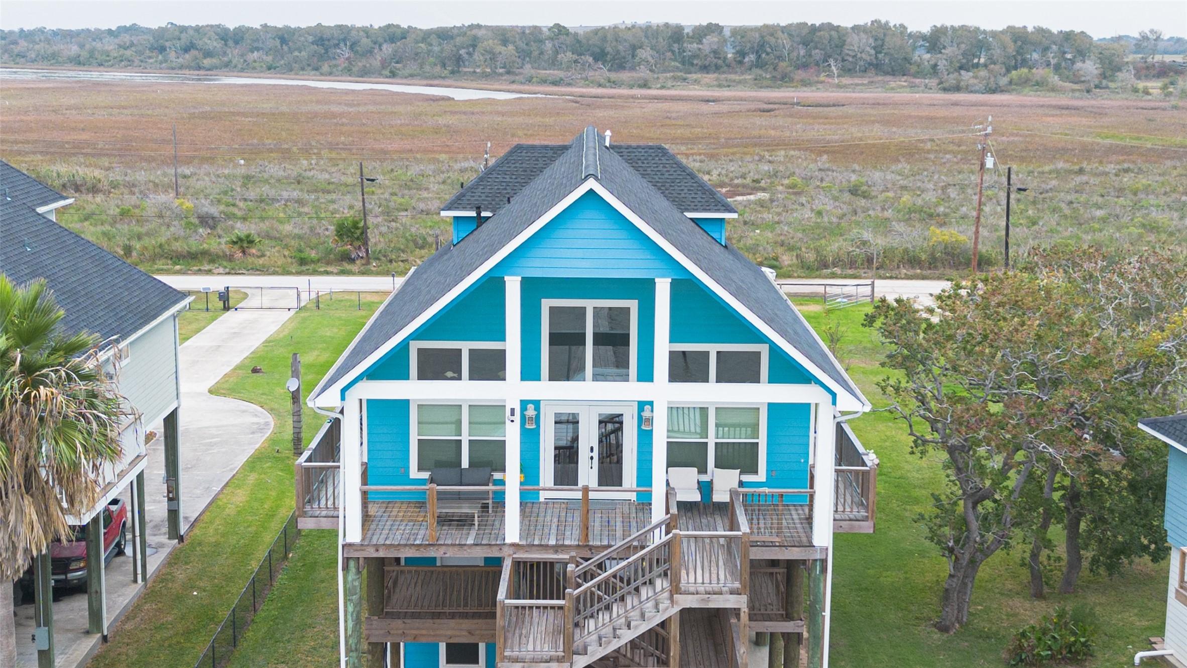 Image 2: Vibrant blue, two-story coastal home with large wi
