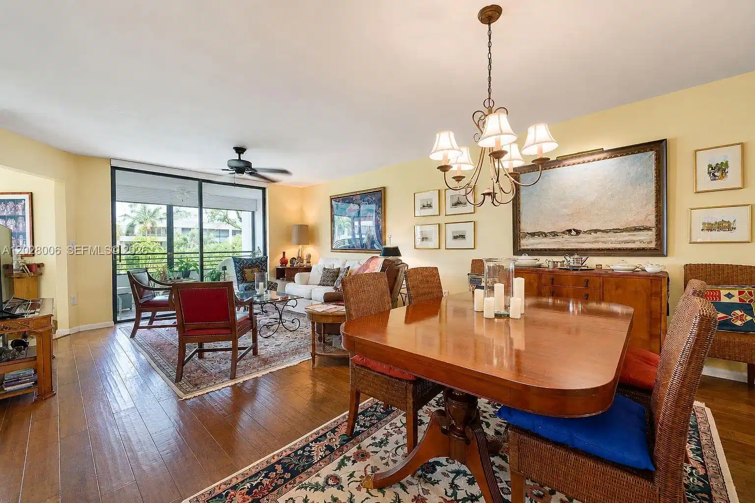 Image 1: The spacious dining-living area features wide-plank wood-like floors and opens to the lanai with vie