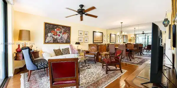 Image 3: The spacious living-dining room features a wall to wall mirror at one end, creating an even more spa