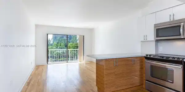Image 3: Modern open kitchen featuring stainless steel appliances, custom cabinetry, and a cozy breakfast bar