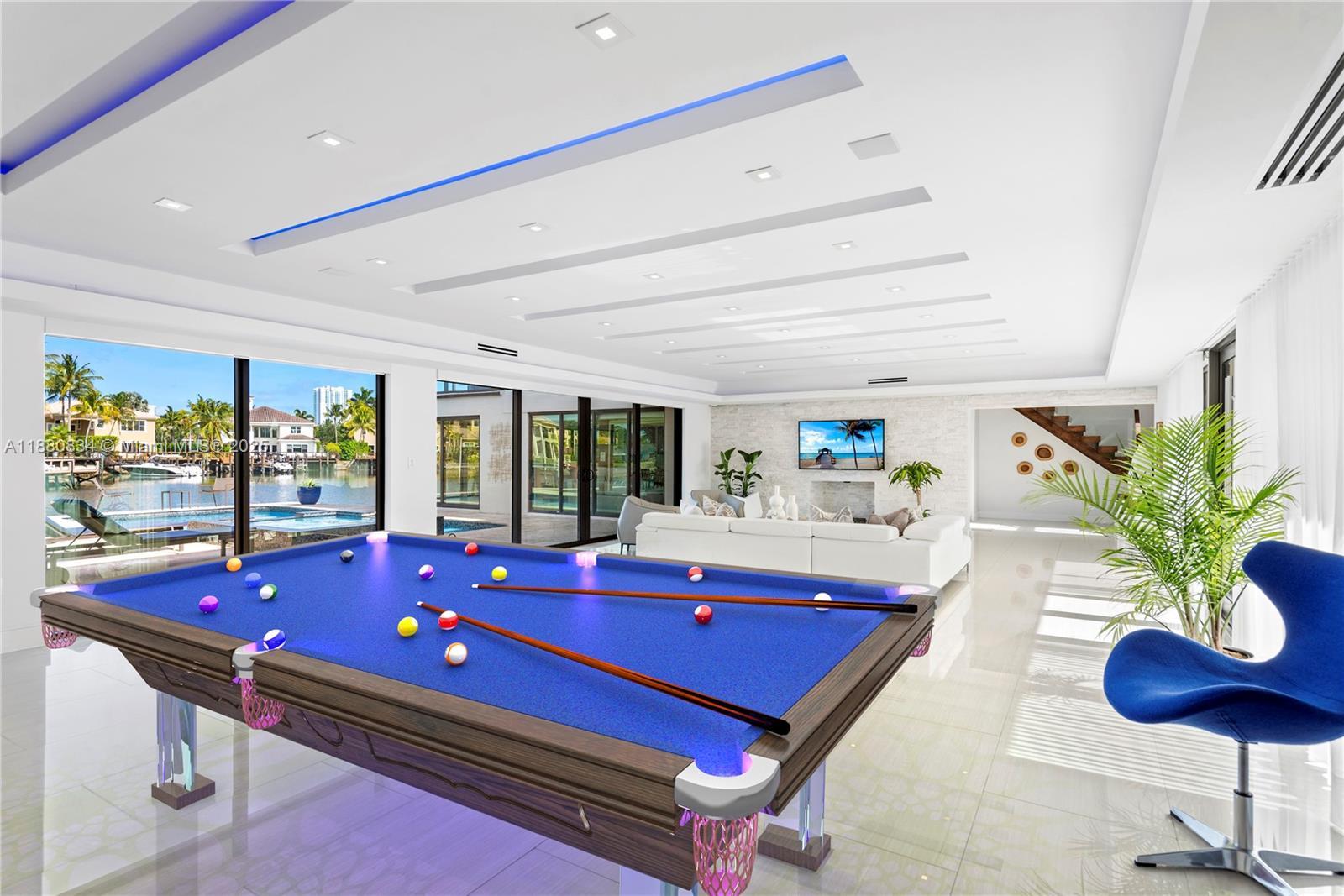 Image 4: Modern game area with a blue felt pool table and accent chairs.