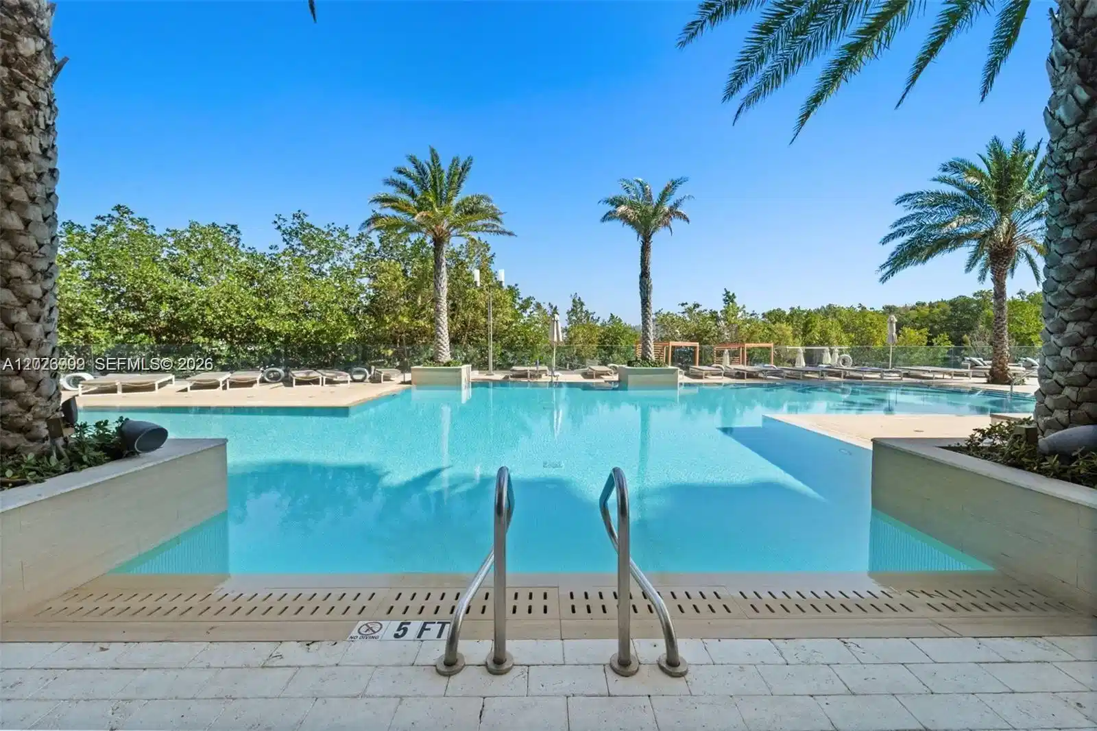 Image 1: Resort-style infinity pool framed by palm trees and sun loungers, offering a peaceful oasis for rela
