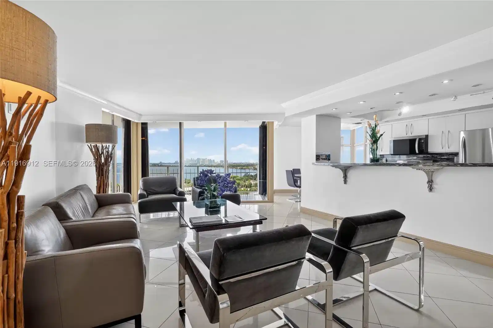 Image 1: An open, sun-filled living space with floor-to-ceiling views that capture both the tranquil waterfro