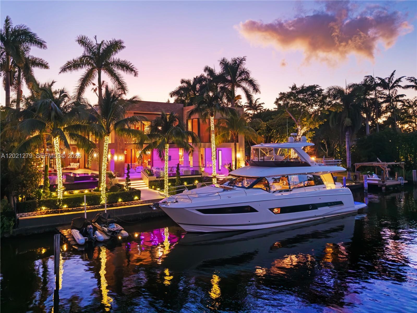Image 2: Ground-level dusk view from canal of private deep-water dock with large motor yacht, illuminated sea