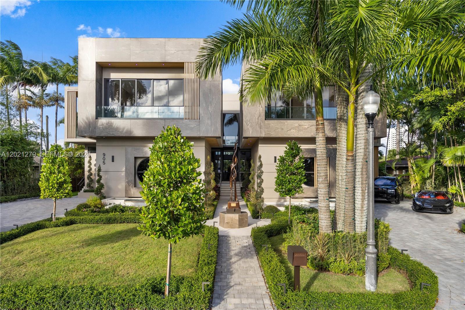 Image 3: Two-story modern luxury home with stone fa&ccedil;ade, paver walkway, bronze sculpture, manicured he