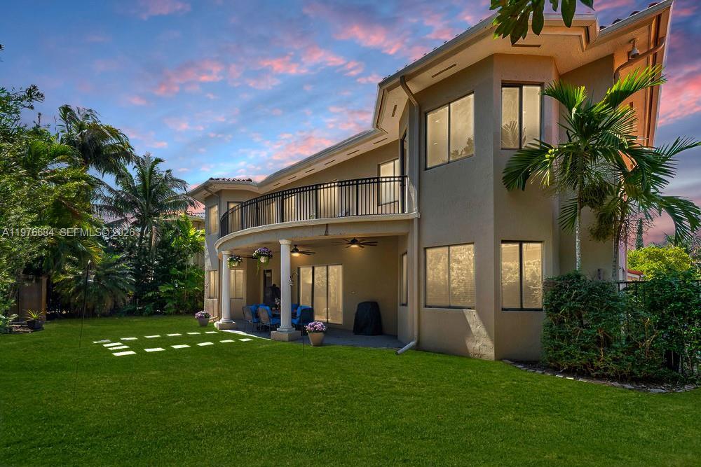 Image 4: The rear exterior of a two-story luxury home at dusk, featuring a curved covered patio with white co