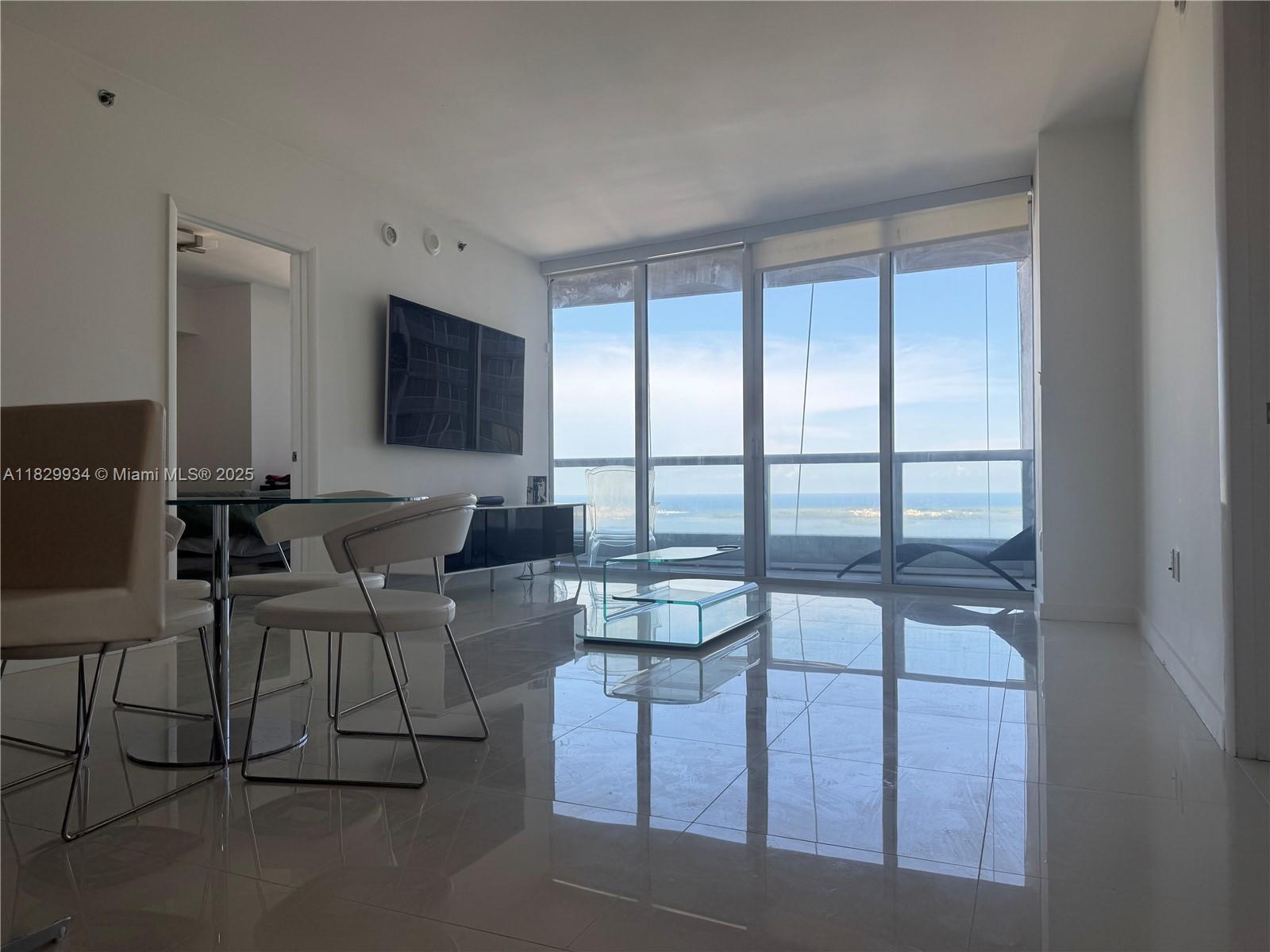 Image 2: Spacious and bright living area with floor-to-ceiling windows showcasing panoramic bay views and sle