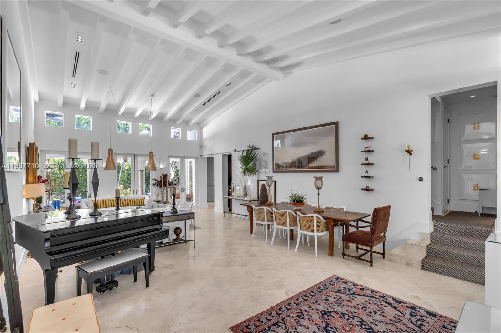 Image 2: The spacious room features a living room and dining room with vaulted ceilings and high ceilings.