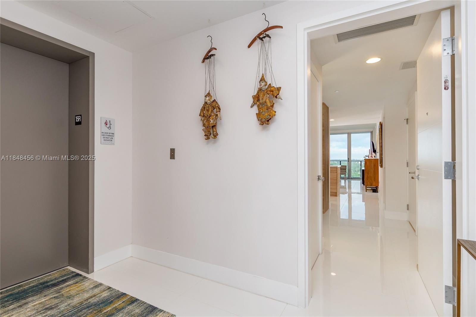 Image 4: Elevator opens to Private Foyer. Door entrance to the condo. White porcelain floors throughout
