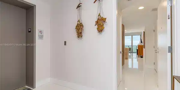 Image 4: Elevator opens to Private Foyer. Door entrance to the condo. White porcelain floors throughout