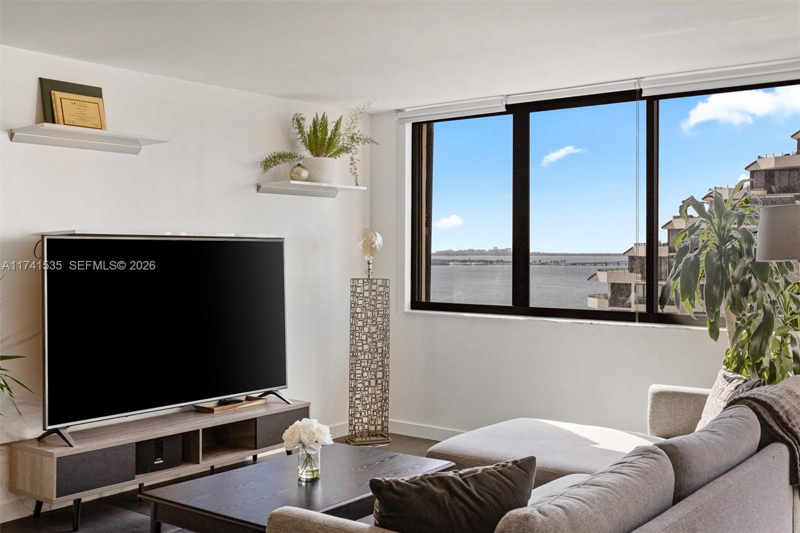Image 3: Step into this bright and open living space, where large windows offer stunning views of Biscayne Ba