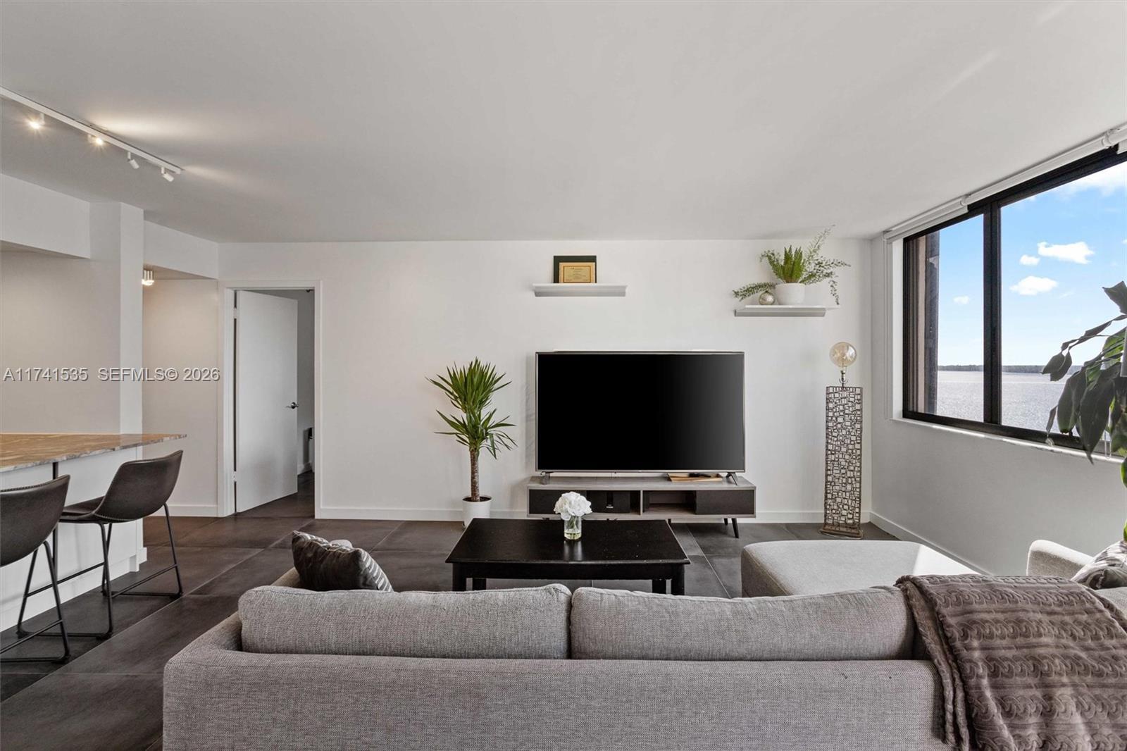 Image 4: The spacious living area seamlessly connects to a stylish kitchen with high-end finishes, making it 