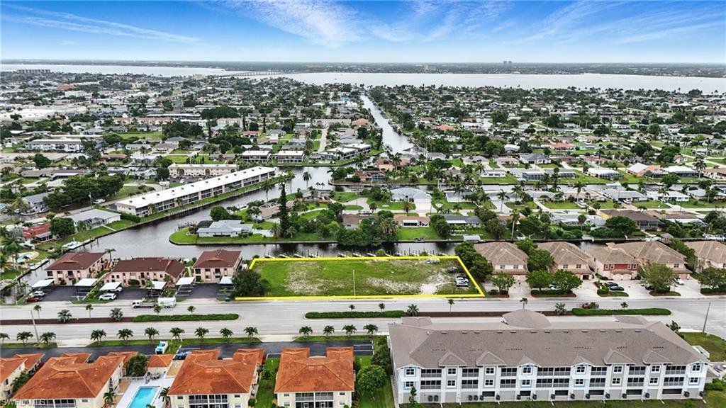 Image 2: Aerial perspective of suburban area featuring property parcel outlined and a large body of water