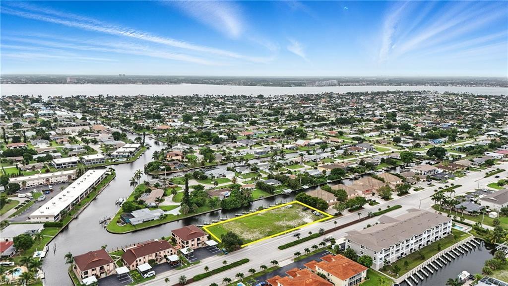 Image 3: Aerial view of residential area featuring property parcel outlined and a large body of water