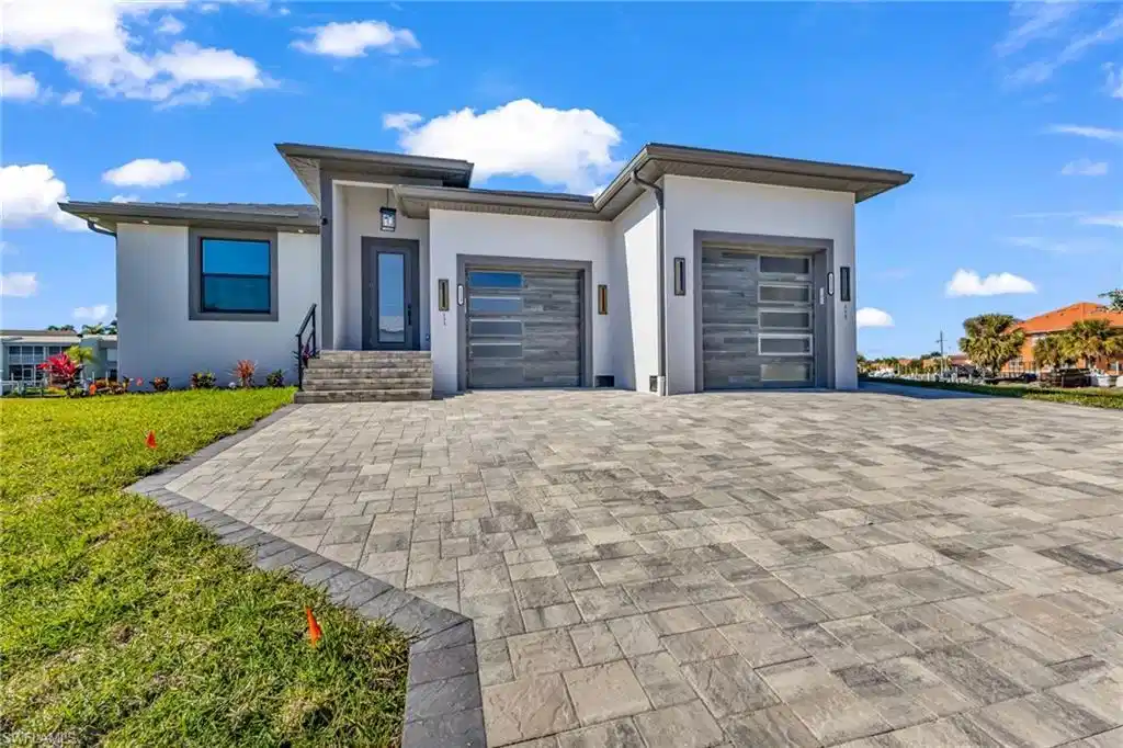 Image 1: View of front of home featuring stucco siding, an attached garage, decorative driveway, and a front lawn
