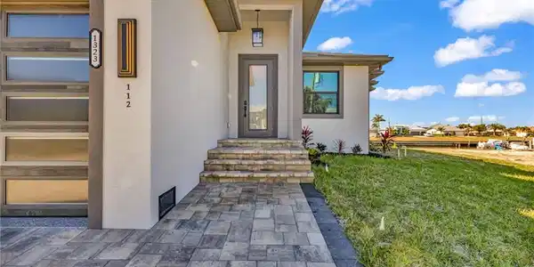Image 4: Doorway to property with stucco siding and a lawn