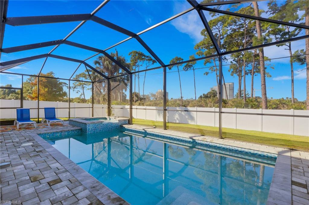 Image 1: View of pool with a sunroom, a lanai, a fenced backyard, a pool with connected hot tub, and a patio area