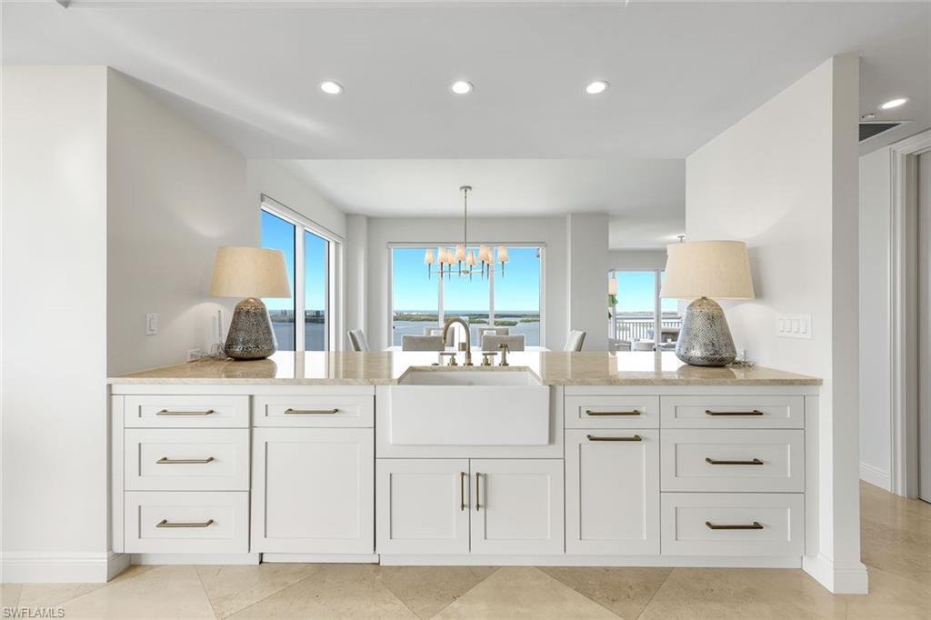 Image 3: Enjoy sweeping water views from the kitchen, where updated appliances and timeless white cabinetry create a bright and refined culinary space.