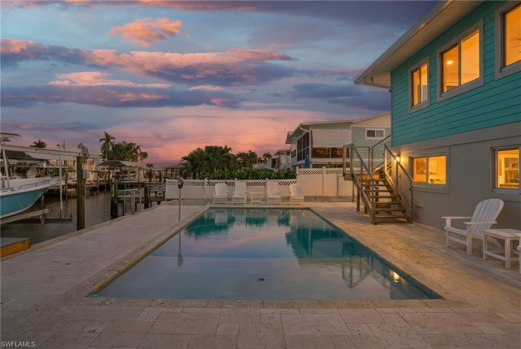 Image 1: Pool at dusk with a patio, stairway, boat lift, a boat dock, and a water view - Virtually Edited Image