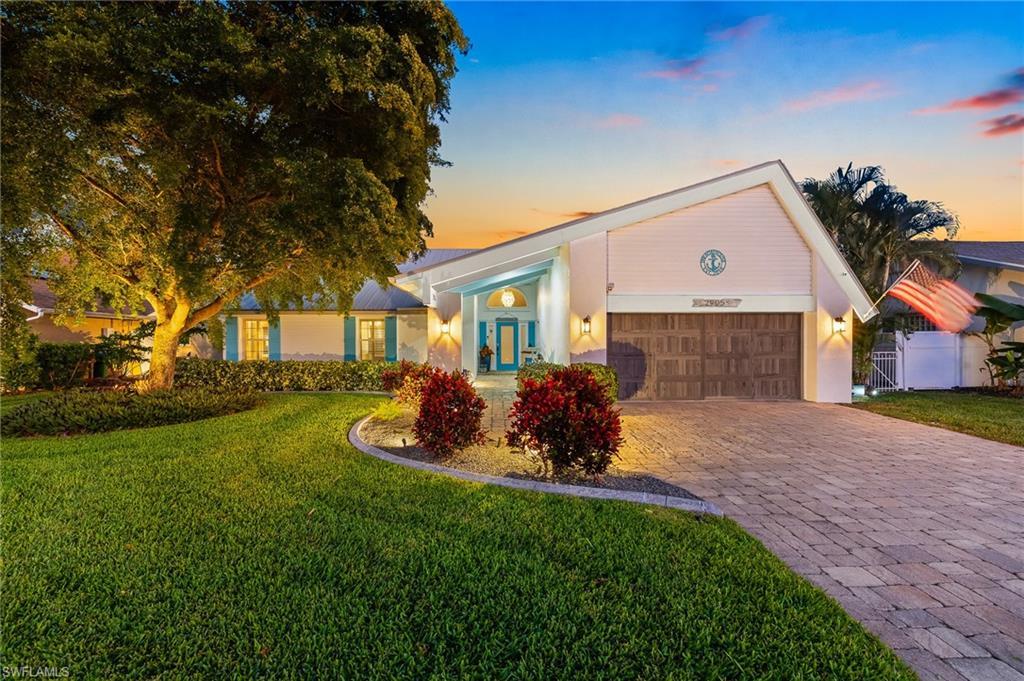 Image 2: View of front facade featuring decorative driveway, a front yard, stucco siding, and a garage