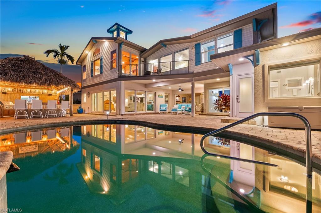 Image 3: Rear view of house featuring a patio area, a balcony, an outdoor pool, and outdoor dining space