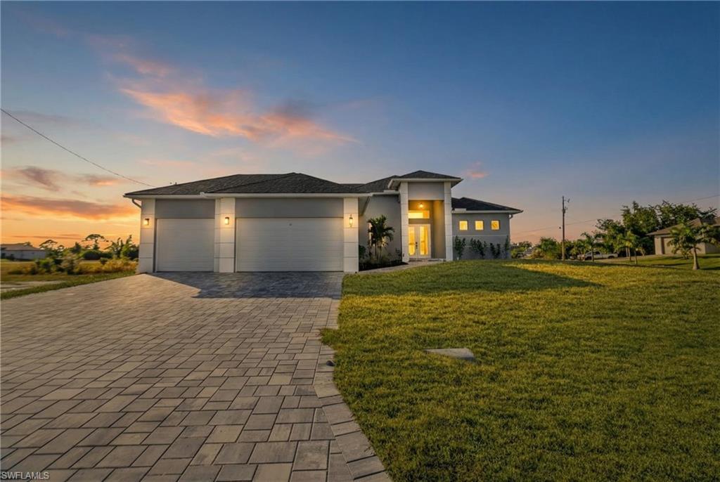 Image 1: Prairie-style home featuring a garage, a front yard, decorative driveway, and stucco siding